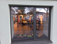 Bewohner*innen treffen sich im Gemeinschafsraum. Durch das Fenster des Raums fotografiert