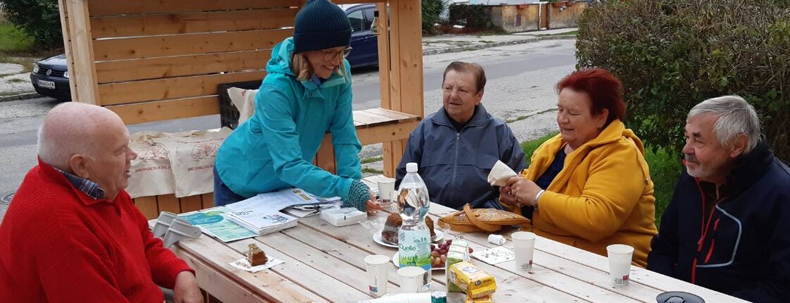 Menschen sitzen um einen Tisch und trinken Kaffee