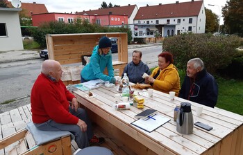 Menschen sitzen um einen Tisch und trinken Kaffee