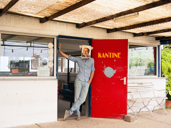 Mann mit einem Gesichtsfoto vor seinem Gesicht steht an der Tür einer Kantine
