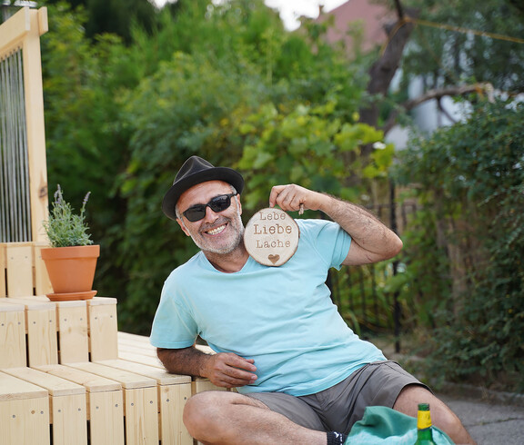 Mann mit Sonnenbrille und einem Schild mit den Worten Lebe, Liebe, Lache