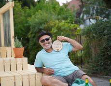 Mann mit Sonnenbrille und einem Schild mit den Worten Lebe, Liebe, Lache